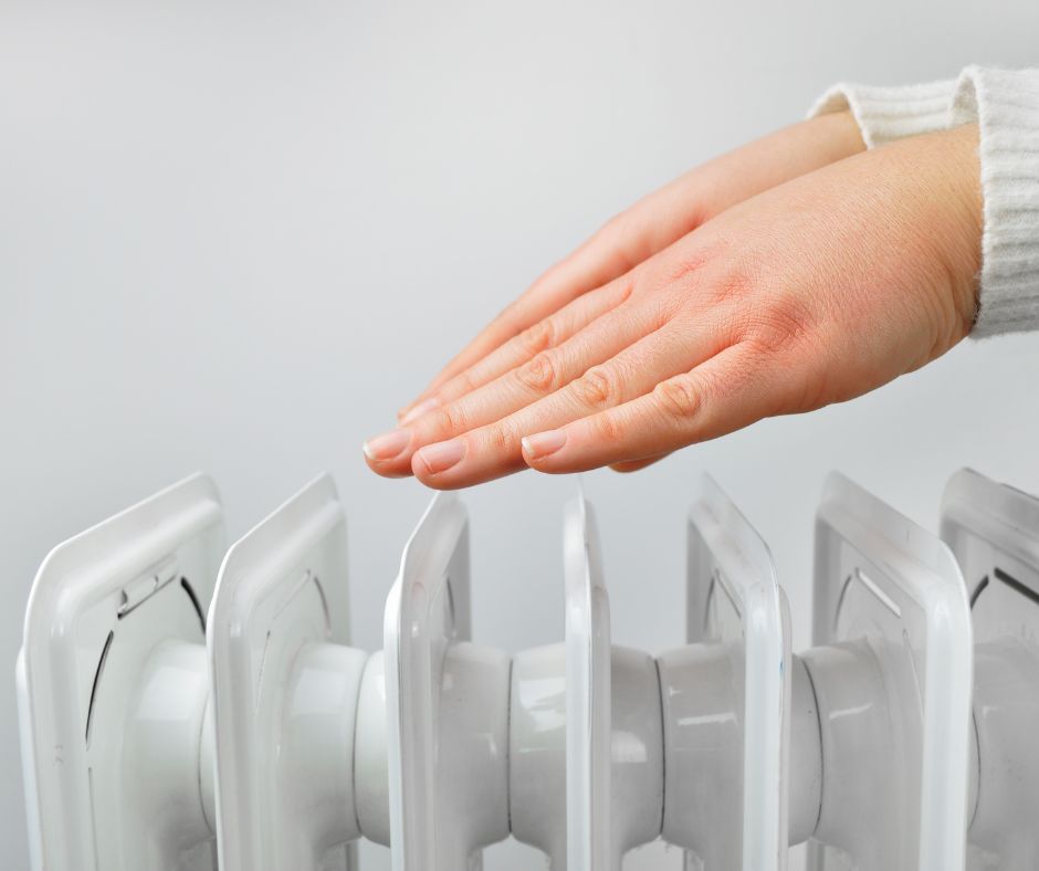 Ruce zahřívající se nad radiátorem