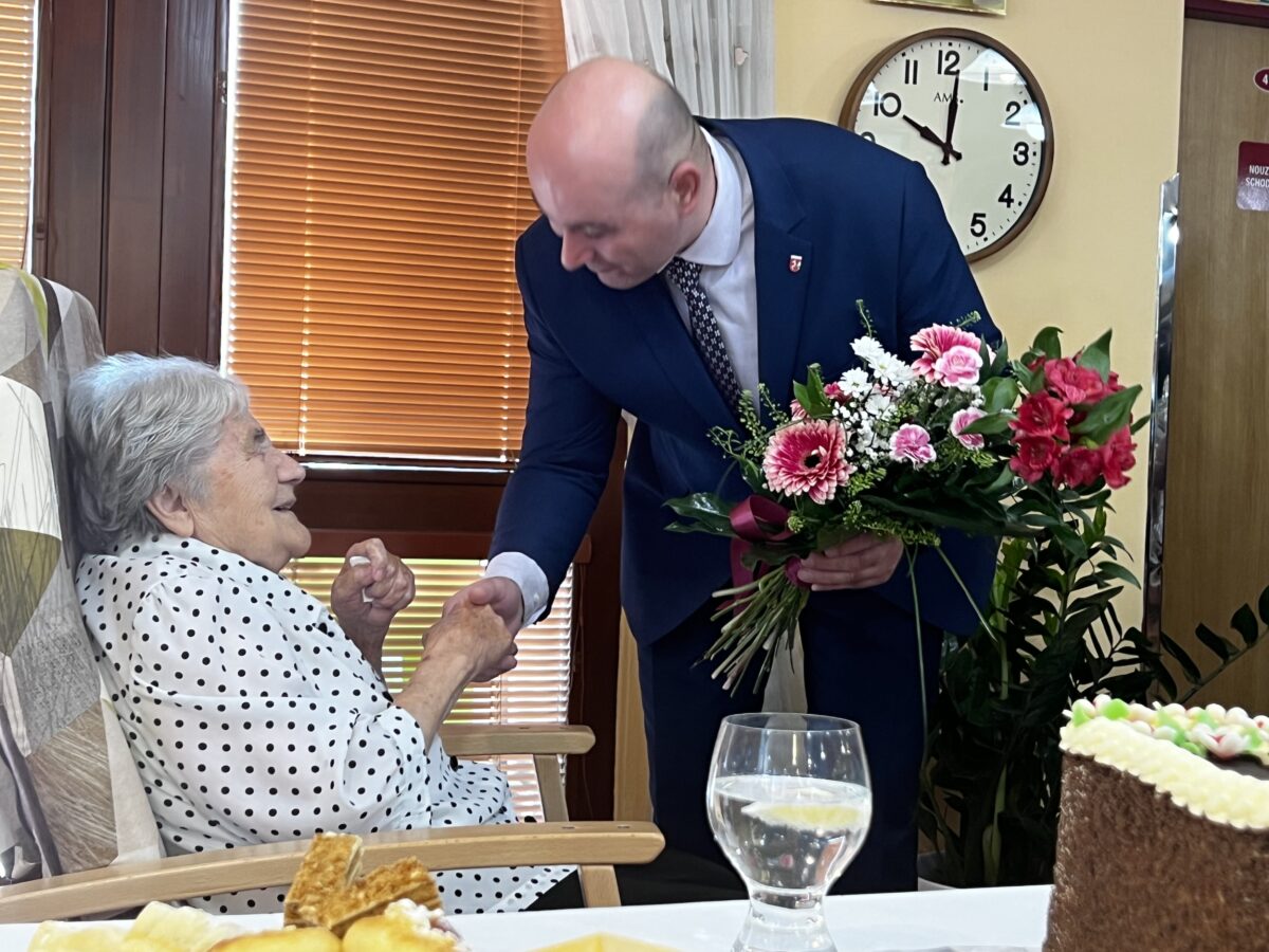 Starosta blahopřející stařence k životnímu jubileu s kyticí v ruce
