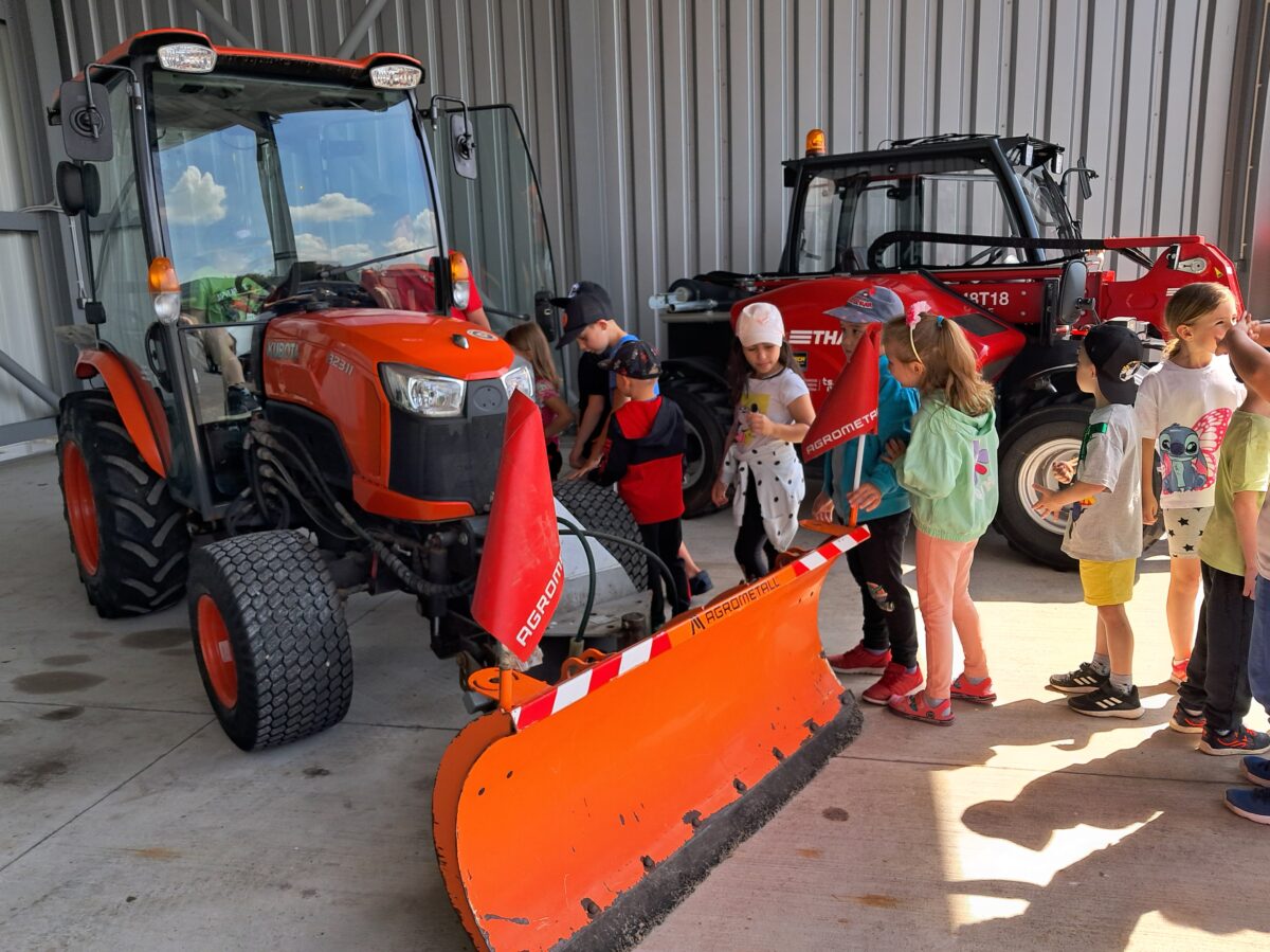 Děti si prohlížejí traktor s radlicí